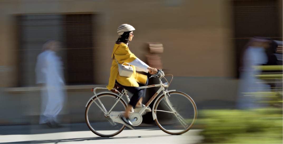 A woman rides a bicycle down a modern urban pathway.