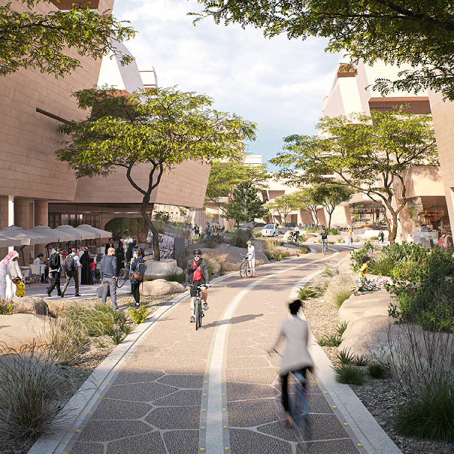 people walking and cycling on a paved path lined with trees and buildings.
