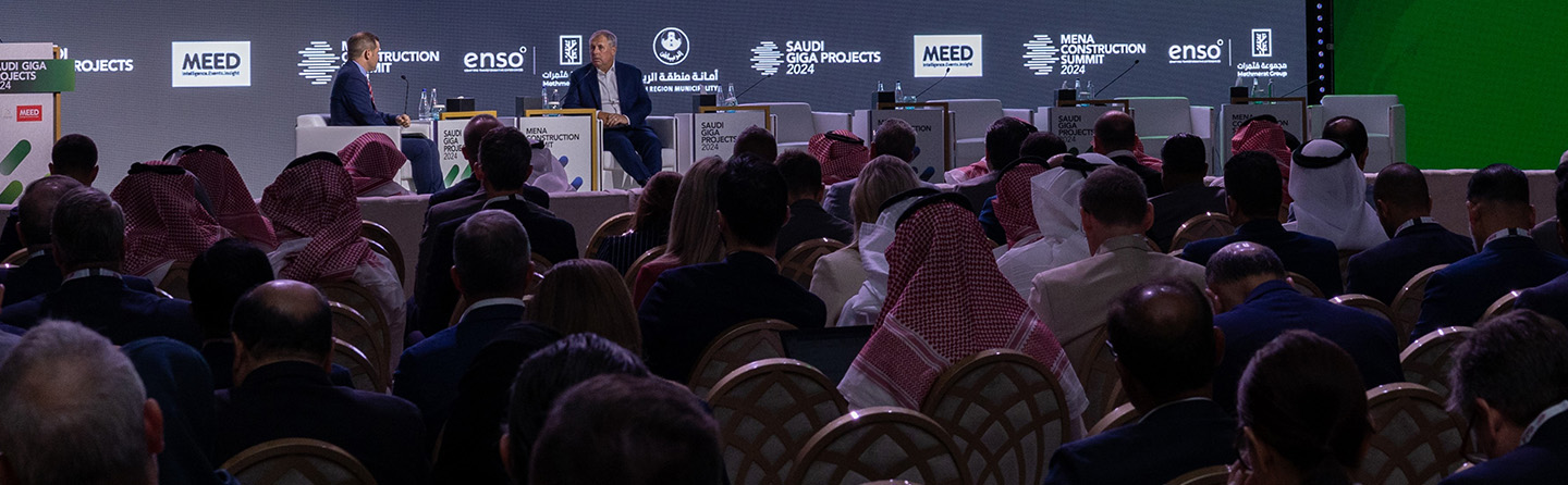 Two panelists at the MEED 2024 Mena Construction Summit Saudi Giga Projects, engaged in a discussion with microphones in front of an audience.